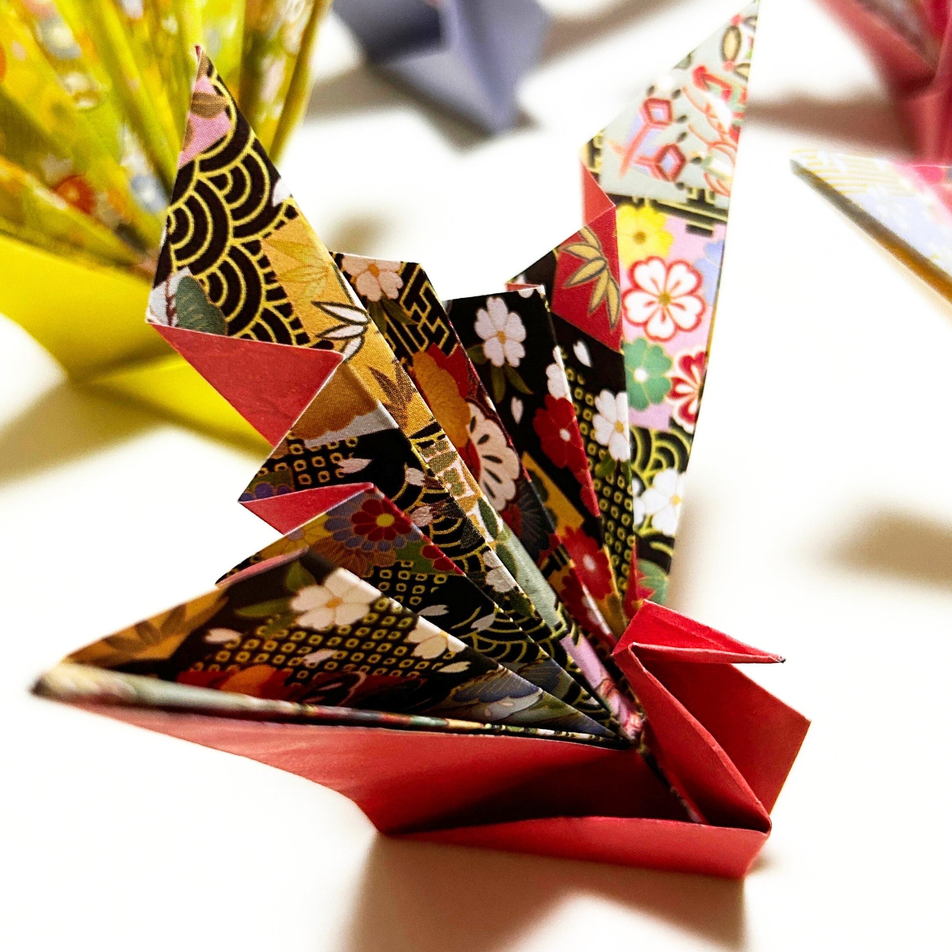 Colorful origami boat with patterned paper on a blurred background