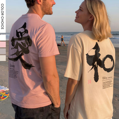 Two people on a beach wearing t-shirts with black calligraphy designs and text.
