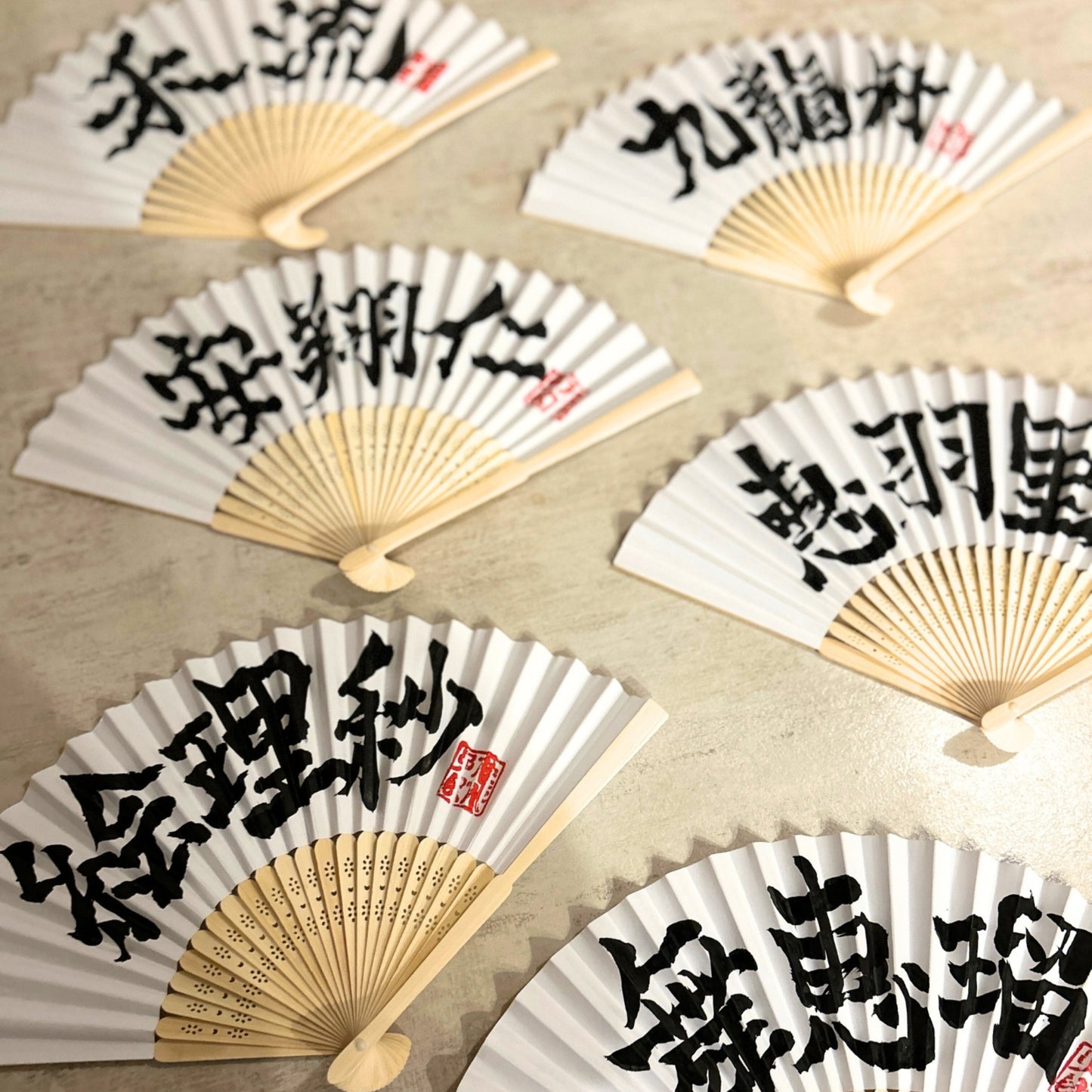 Set of folding fans with Japanese characters on a beige surface