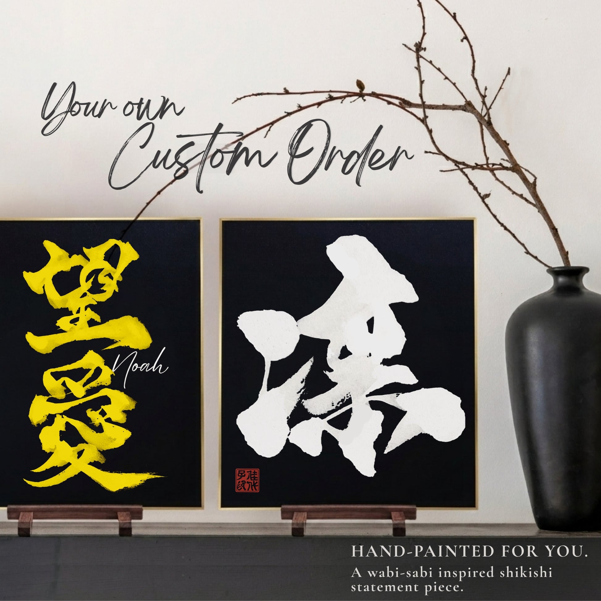 Two hand-painted artworks with gold and white Japanese calligraphy on traditional black Shikishi boards, displayed against a neutral wall with a vase and branch.