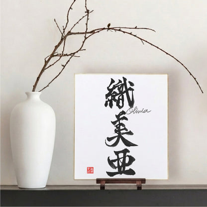 Japanese calligraphy artwork on a stand with a white vase and branches in the background